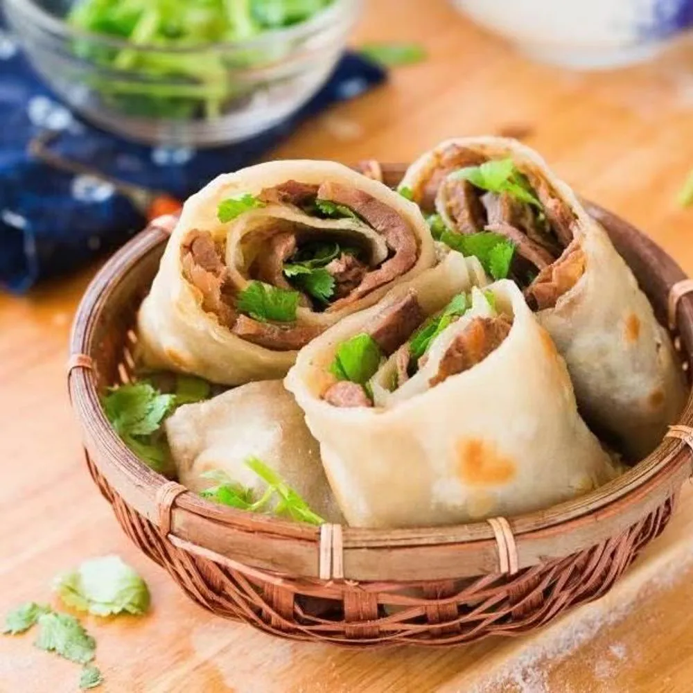 Soft beef wrap rolls filled with tender beef and fresh cilantro in bamboo basket at Noodles + BBQ, a Chinese Restaurant in Los Angeles