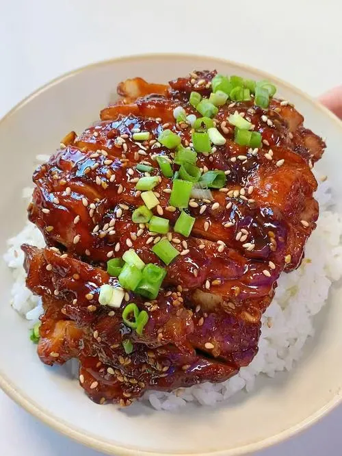 Glazed barbecue pork belly rice bowl topped with green onions and white sesame seeds at Noodles + BBQ, a Chinese Restaurant in Los Angeles Glazed barbecue pork belly rice bowl topped with green onions and white sesame seeds at Noodles + BBQ, a Chinese Restaurant in Los Angeles